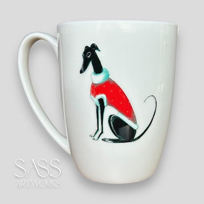 White mug with a black greyhound or whippet wearing a red sweater design on a light gray background, featuring 'SASS Artworks' branding.