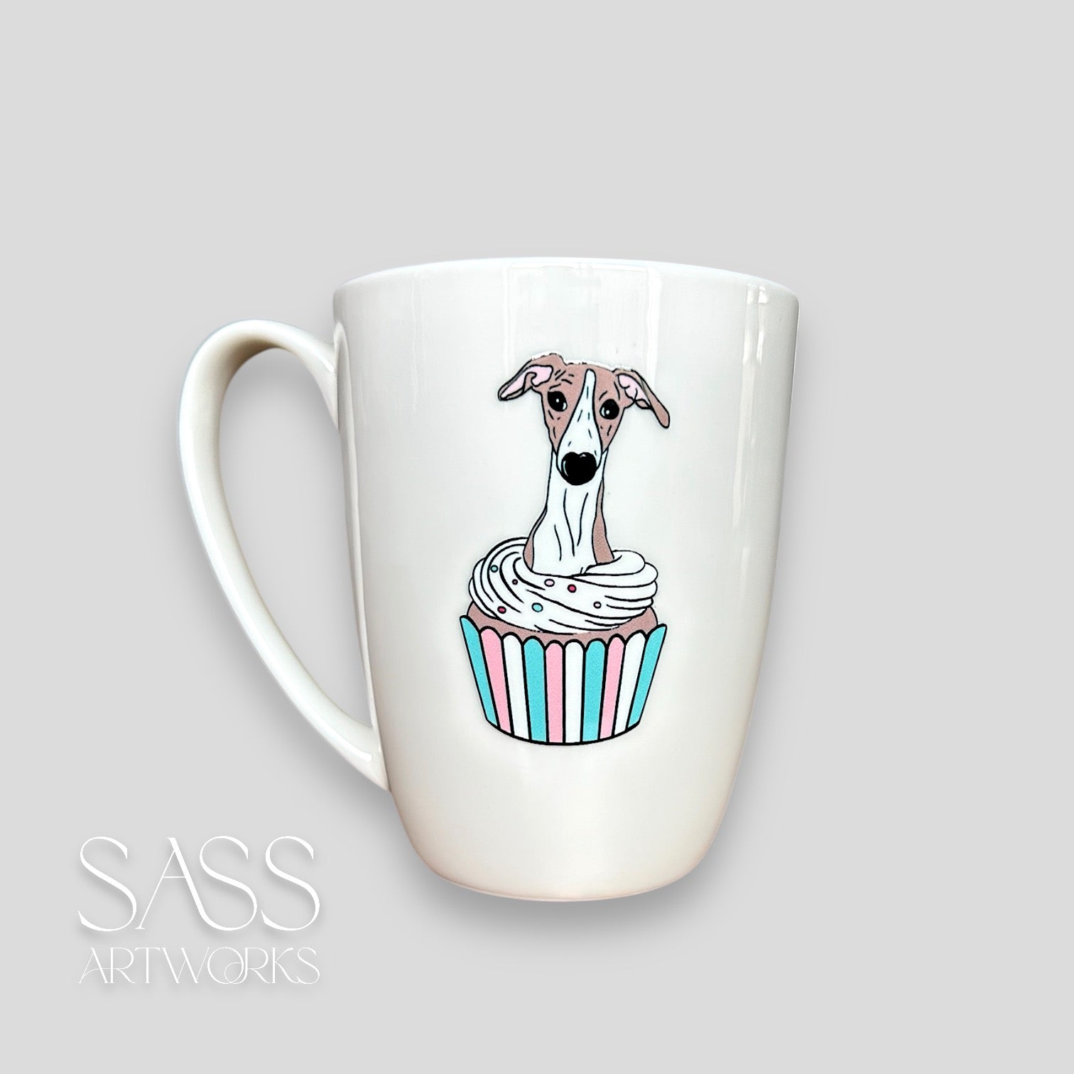 White mug with a whippet  in a cupcake design on a light grey background, featuring the brand 'SASS Artworks'.