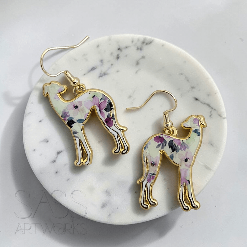 Floral dog-shaped earrings on a marble coaster with 'SASS Artworks' branding.