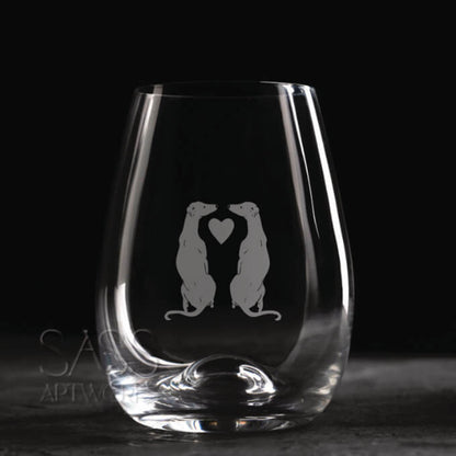 Clear glass with engraved design of two animals holding a heart on a dark background