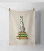 Tea towel with a whippet seated on a stack of books  on a white background