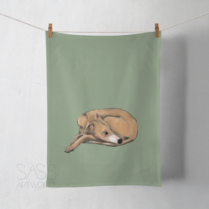 Green tea towel with a whippet illustration hanging on a line against a white wall.